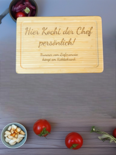 Holztafel mit der Aufforderung "Hier kocht der Chef persönlich!" und frischen Zutaten.
